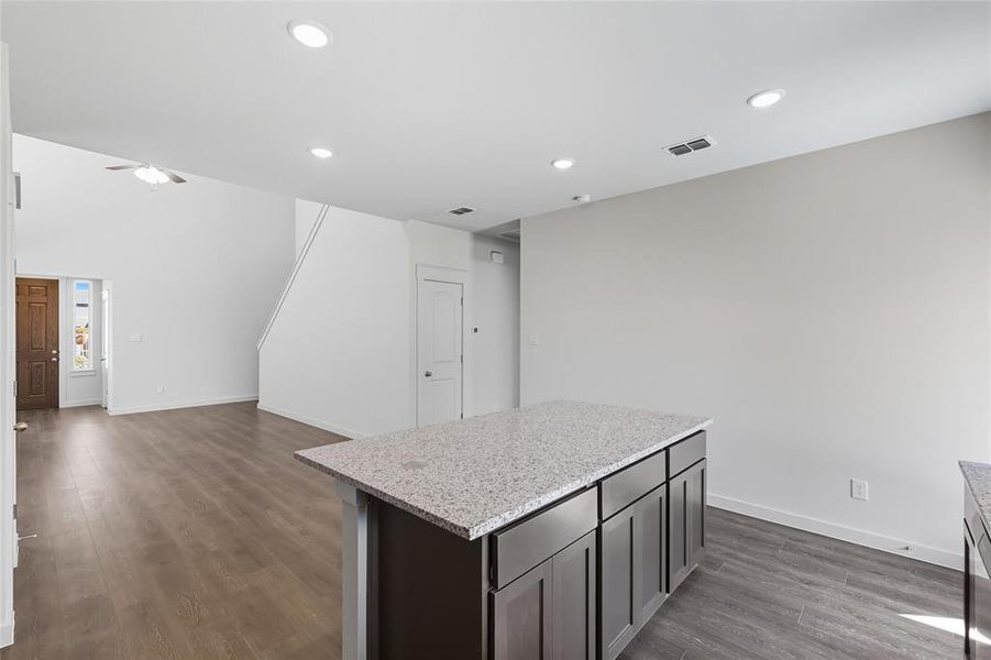Kitchen with light stone counters, dark wood-style flooring, a center island, recessed lighting, and ceiling fan Kitchen with light stone counters, dark wood-style flooring, a center island, recessed lighting, and ceiling fan