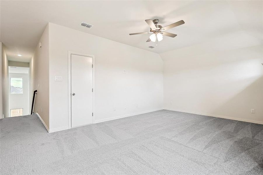 Carpeted spare room featuring lofted ceiling and ceiling fan