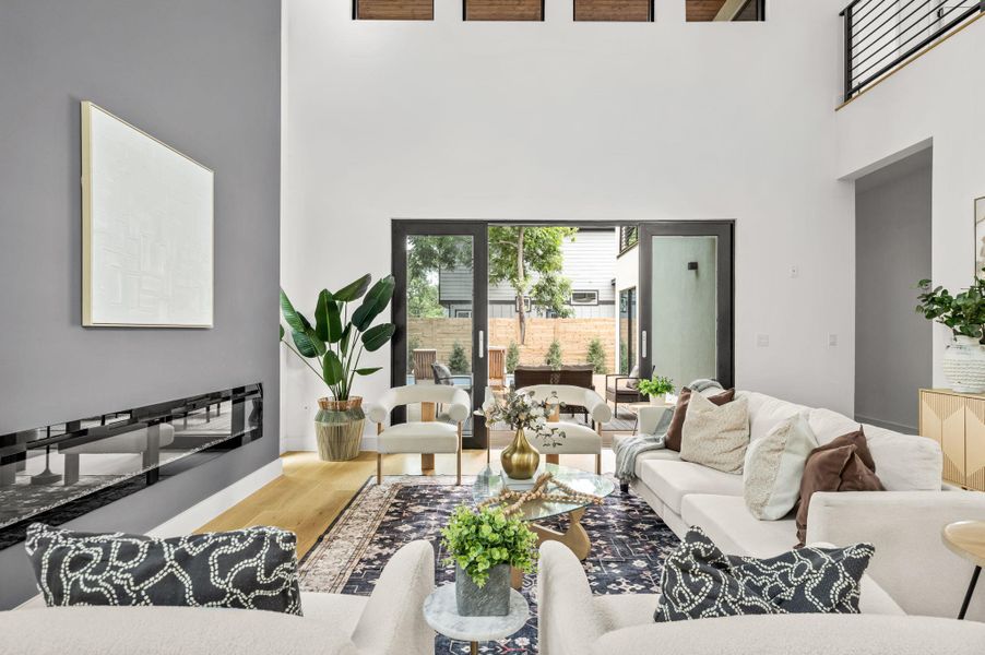 A spacious living room features soaring ceilings, a sleek linear fireplace, and expansive sliding glass doors opening to the outdoors. A spacious living room features soaring ceilings, a sleek linear fireplace, and expansive sliding glass doors opening to the outdoors.