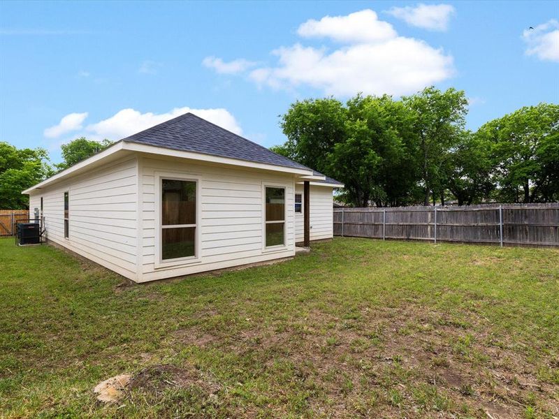 Rear view of house featuring a fenced backyard and a shingled roof