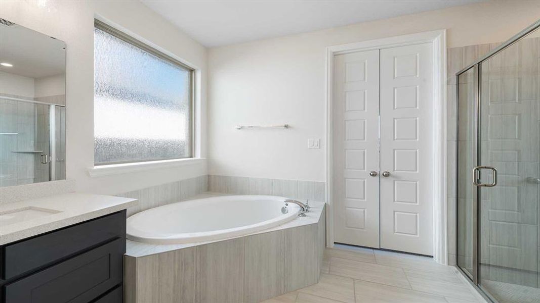 Bathroom with separate shower and tub, tile patterned floors, and vanity