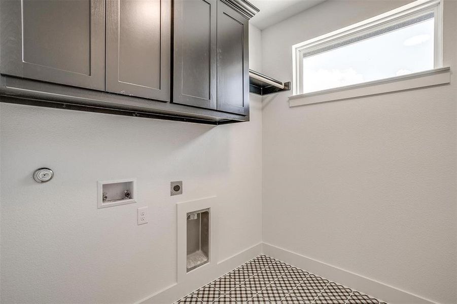 Clothes washing area featuring cabinets, tile patterned floors, electric dryer hookup, and washer hookup