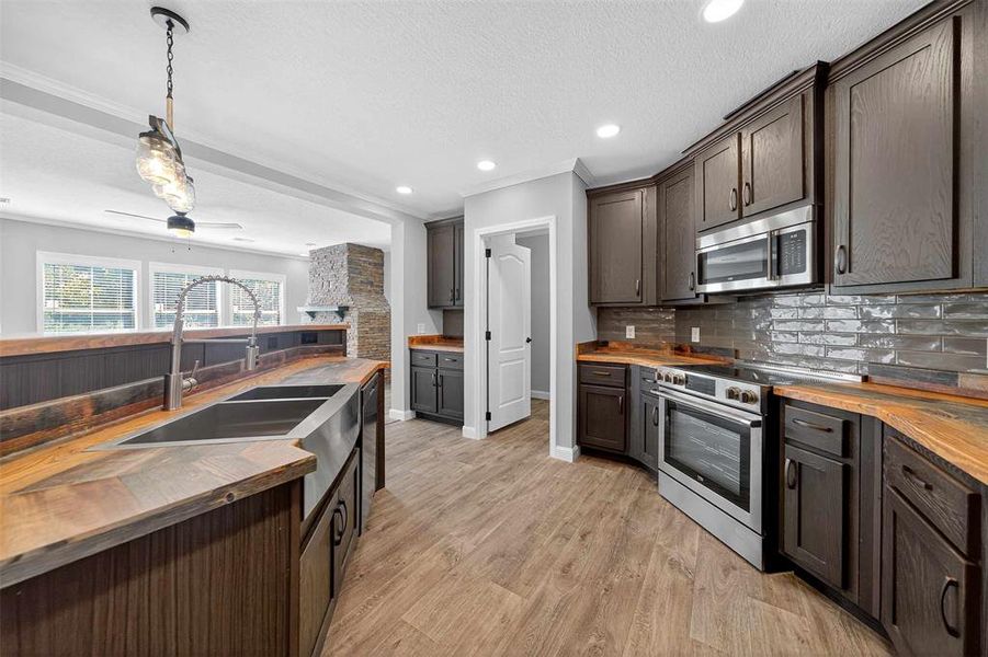 Kitchen with wooden counters, hanging light fixtures, stainless steel appliances, a textured ceiling, and recessed lighting Kitchen with wooden counters, hanging light fixtures, stainless steel appliances, a textured ceiling, and recessed lighting