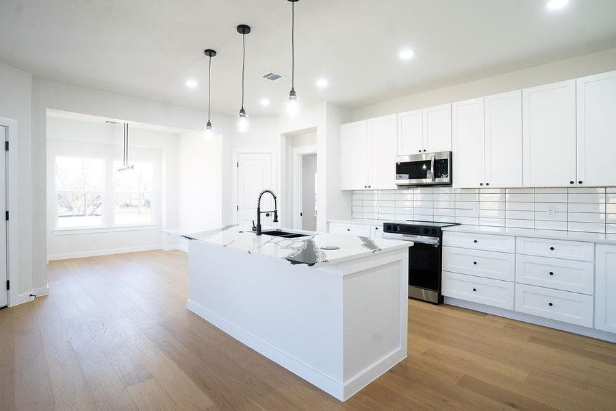 Kitchen featuring a kitchen island with sink, pendant lighting, range with electric cooktop, white cabinets, and decorative backsplash