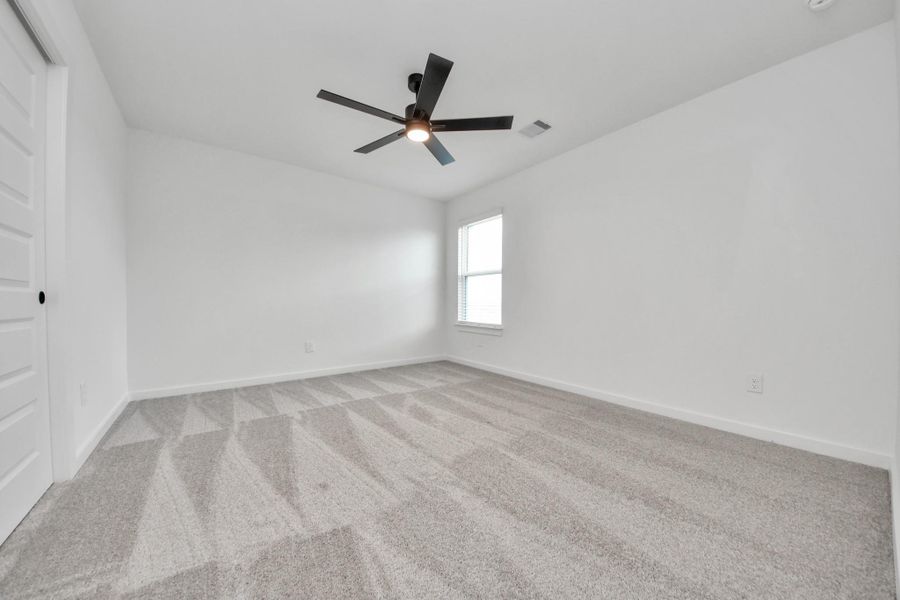 Secondary bedroom features plush carpeting, large windows that let in plenty of natural light, bright paint, and spacious closets. Sample photo of completed home with similar floor plan. Actual colors and selections may vary. Secondary bedroom features plush carpeting, large windows that let in plenty of natural light, bright paint, and spacious closets. Sample photo of completed home with similar floor plan. Actual colors and selections may vary.