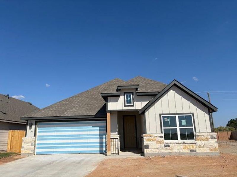 View of front of home with a shingled roof, stone siding, concrete driveway, an attached garage, and board and batten siding View of front of home with a shingled roof, stone siding, concrete driveway, an attached garage, and board and batten siding