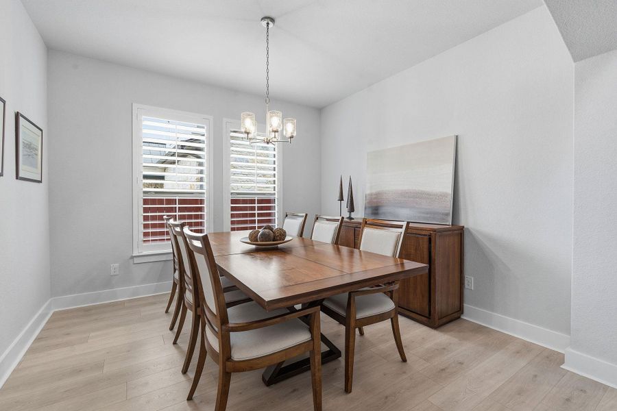 Dining room with light wood finished floors and hanging lights