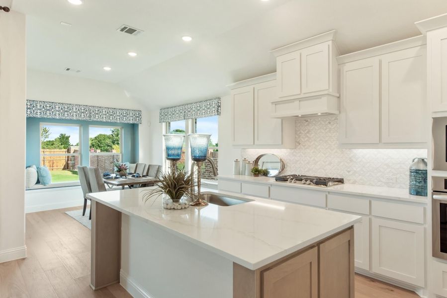 Kitchen with white cabinets, center island, quartz countertops, and tile backsplash open to dining area Kitchen with white cabinets, center island, quartz countertops, and tile backsplash open to dining area