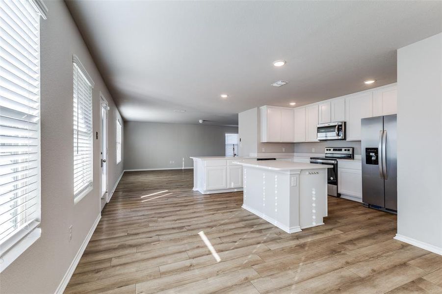 Kitchen with a center island, kitchen peninsula, light hardwood / wood-style floors, white cabinetry, and stainless steel appliances