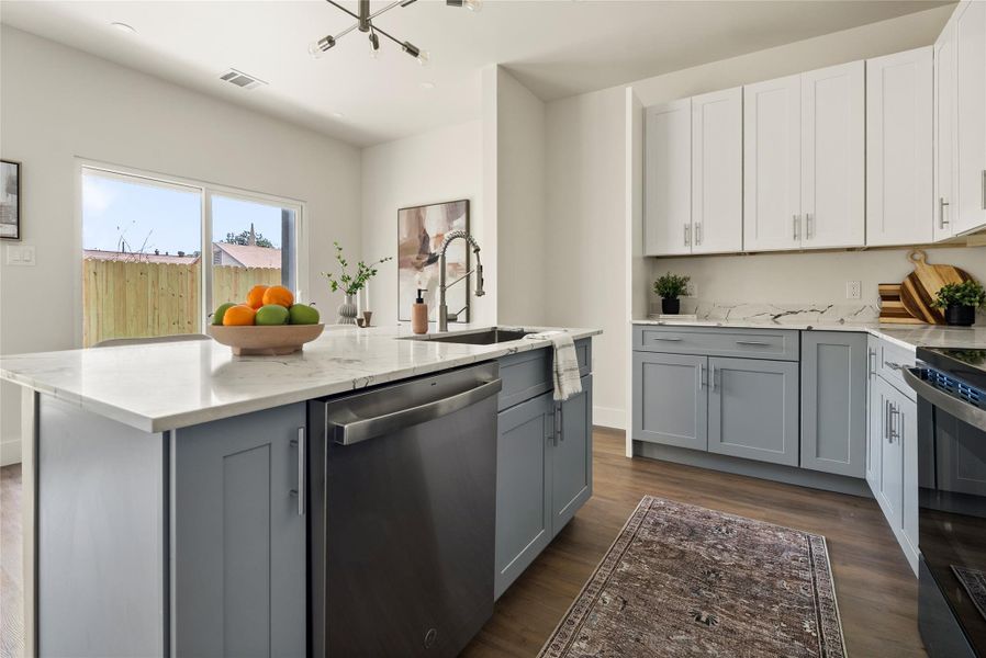 A well-appointed kitchen showcasing an island with a sink, sleek cabinetry, and a view of the private outdoor space.