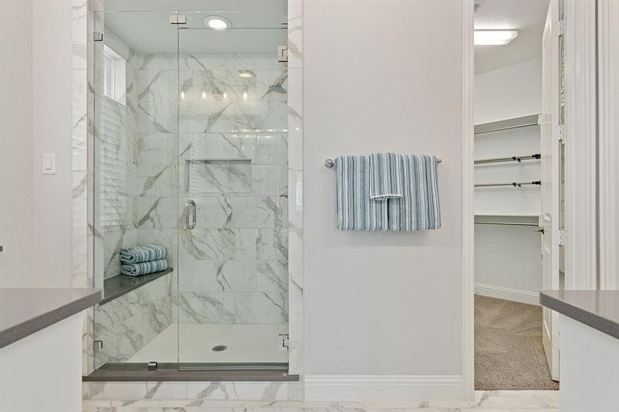 Primary bathroom featuring an enclosed shower, tile flooring, and a large walk in closet