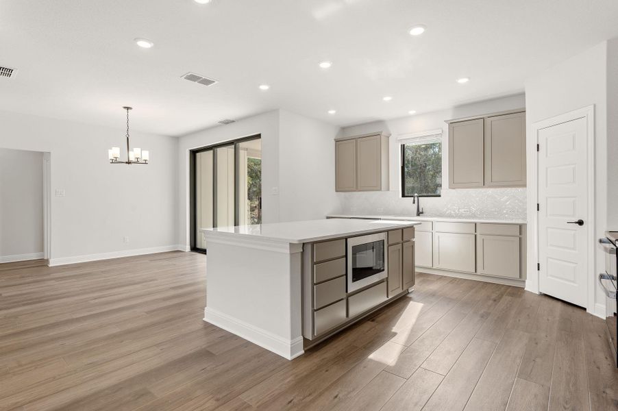 Spacious kitchen featuring built in microwave drawer, large center island, abundant storage, breakfast bar, eat-in kitchen dining area, modern style range hood, stainless appliances, and pantry
