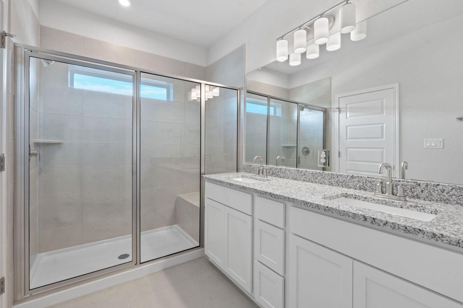 Bathroom featuring a shower stall, double vanity, and tile patterned floors