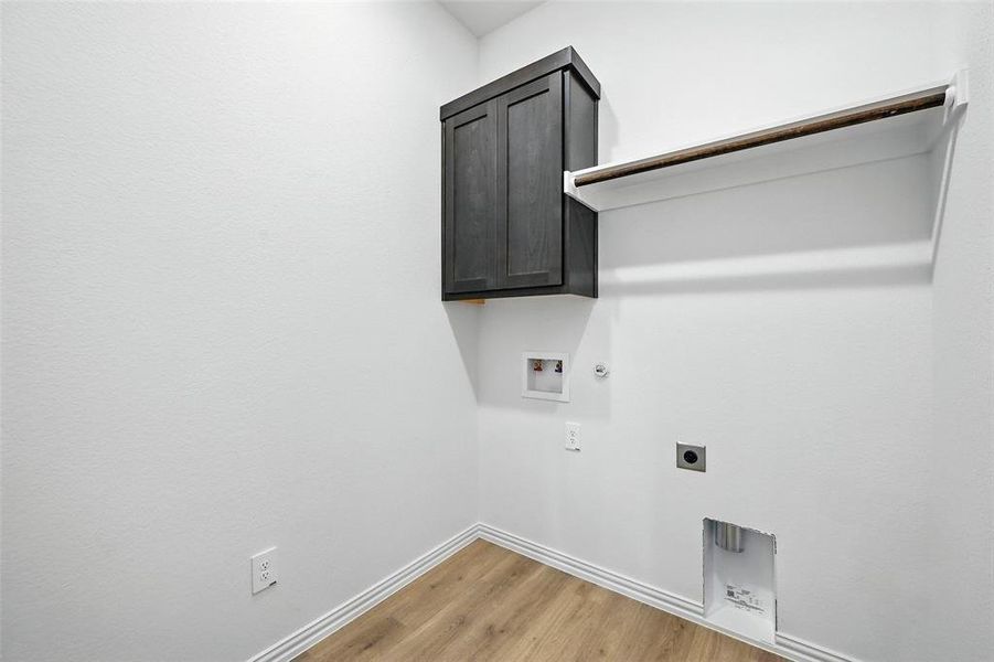 Laundry area featuring gas dryer hookup, hookup for an electric dryer, washer hookup, light wood-style floors, and cabinet space