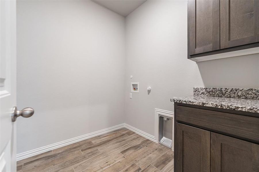 Laundry area featuring gas dryer hookup, light wood finished floors, hookup for a washing machine, and cabinet space Laundry area featuring gas dryer hookup, light wood finished floors, hookup for a washing machine, and cabinet space
