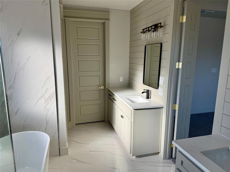 Bathroom featuring vanity, a freestanding bath, and light marble finish floors