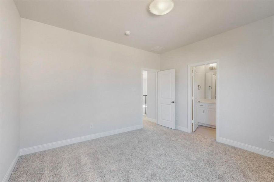 Unfurnished bedroom featuring light carpet and ensuite bath