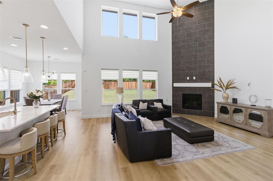 Spacious living area featuring a vaulted ceiling with a ceiling fan, a floor-to-ceiling tile fireplace, and wood-finish flooring
