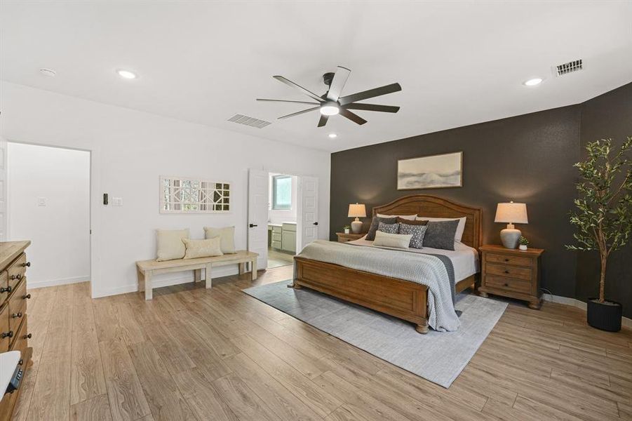 Bedroom with light wood-style flooring, ceiling fan, an accent wall, and recessed lighting