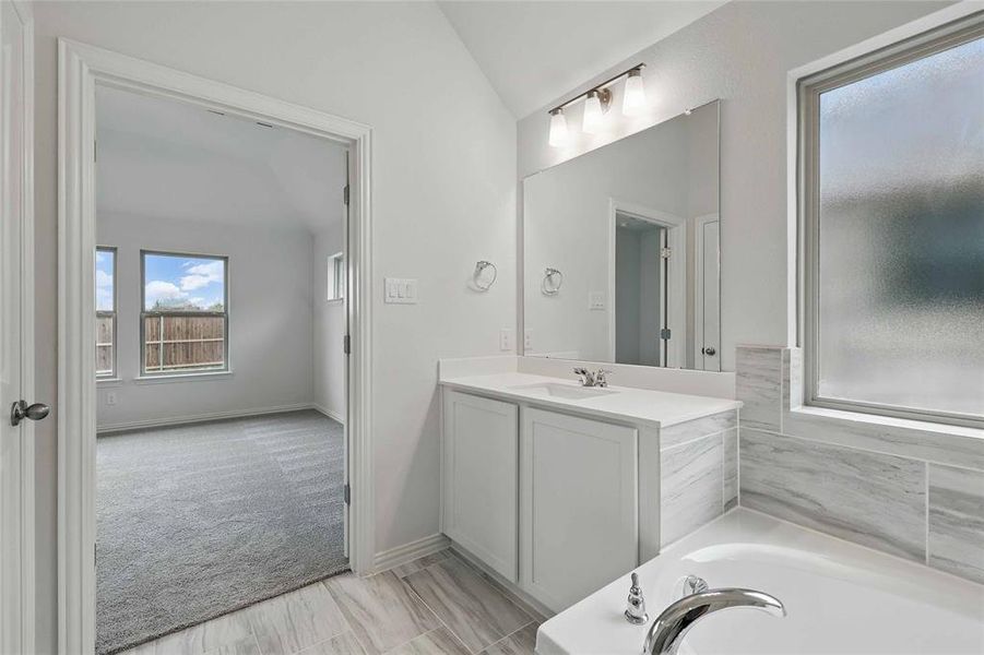 Bathroom with vaulted ceiling, a garden tub, and vanity Bathroom with vaulted ceiling, a garden tub, and vanity
