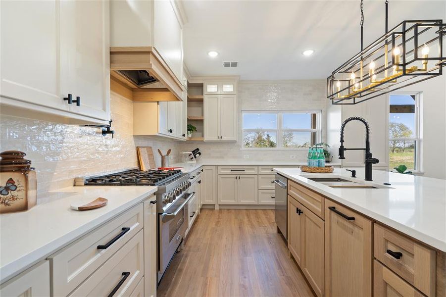 Kitchen with a wealth of natural light, sink, stainless steel appliances, and custom range hood