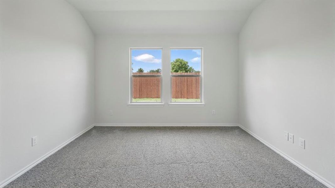 Spare room featuring lofted ceiling and light carpet