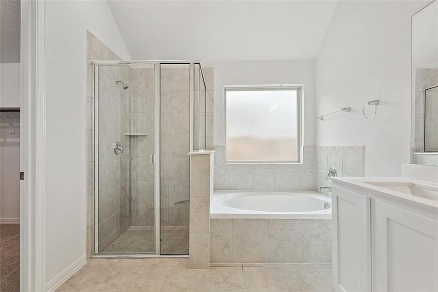 Bathroom with tile floors, vanity, plus walk in shower, and vaulted ceiling