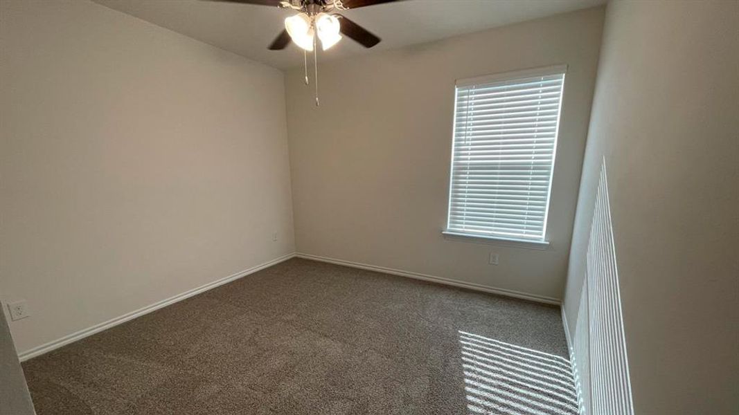 Interior space featuring neutral wall paint, gray carpeting, a ceiling fan with integrated lighting, and a single window with horizontal blinds