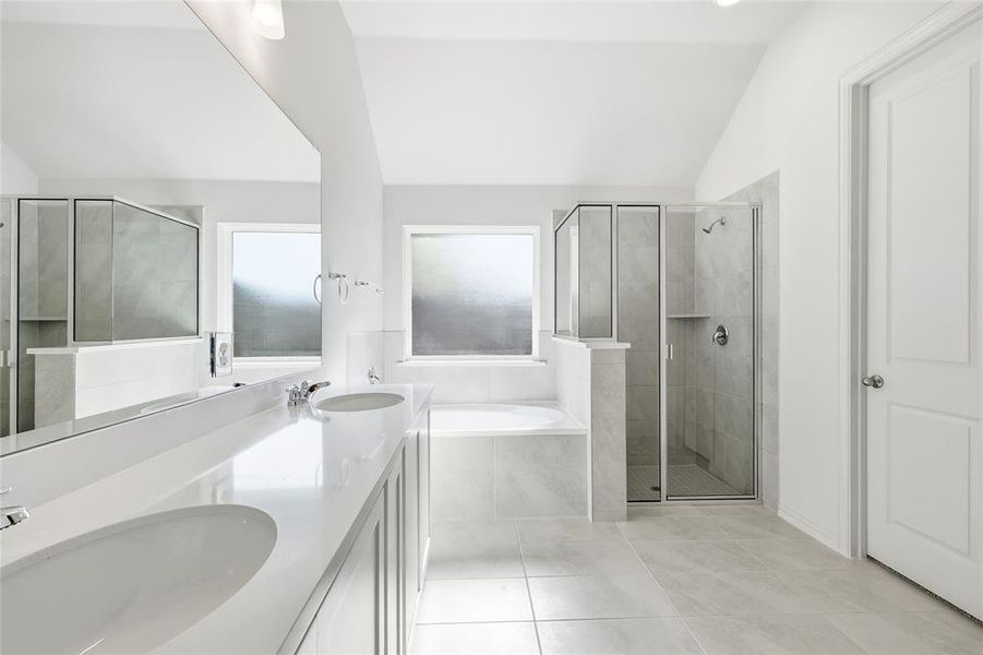Full bathroom featuring a bath, vaulted ceiling, double vanity, a shower stall, and light tile patterned flooring