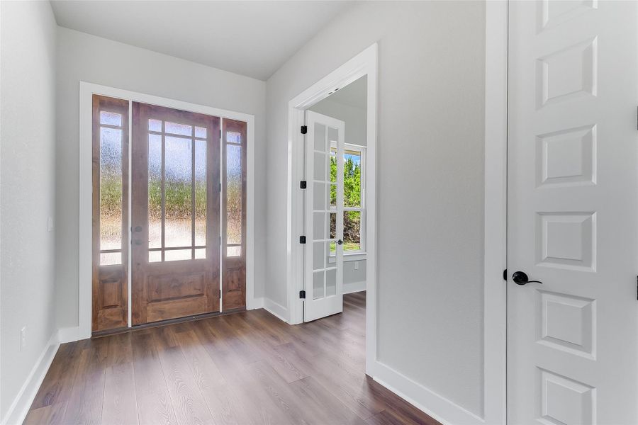 Foyer entrance with dark wood-style flooring and baseboards