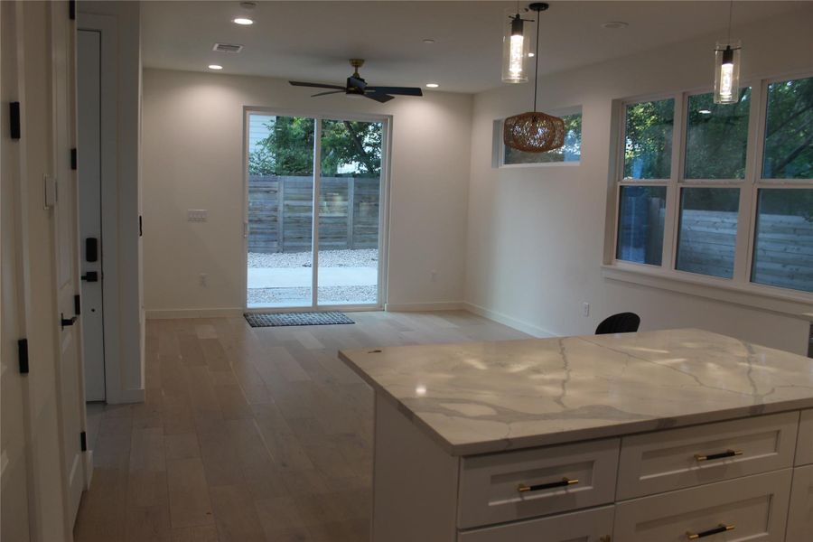 Natural light floods this modern living area featuring a kitchen island and a sliding glass door.