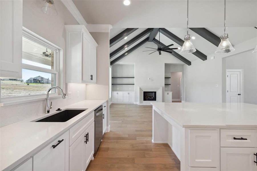 Kitchen featuring white cabinetry, sink, vaulted ceiling with beams, light hardwood / wood-style flooring, and dishwasher