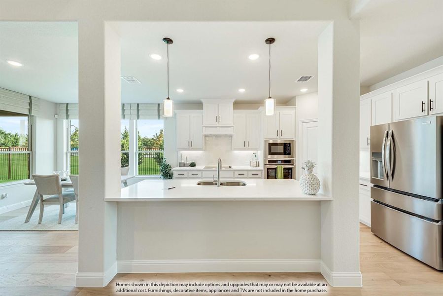 Open kitchen with white cabinets, quartz island, pendant lights, and stainless steel appliances