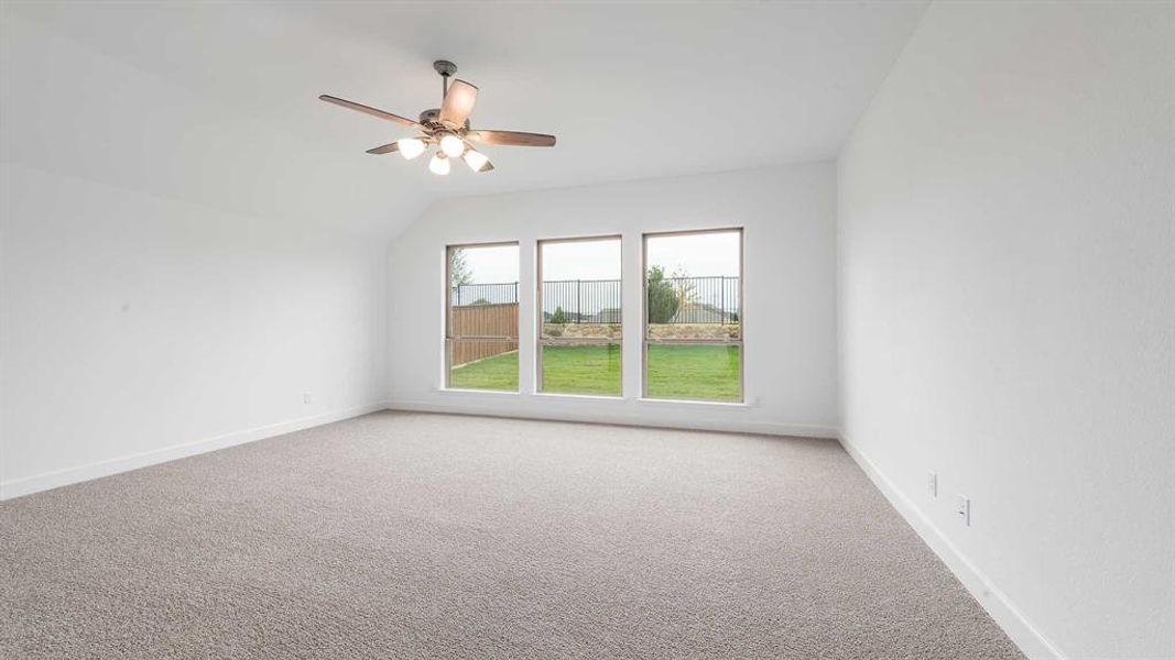 Carpeted spare room with ceiling fan and lofted ceiling