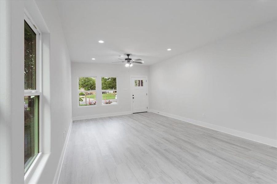 Empty room with ceiling fan and light hardwood / wood-style floors