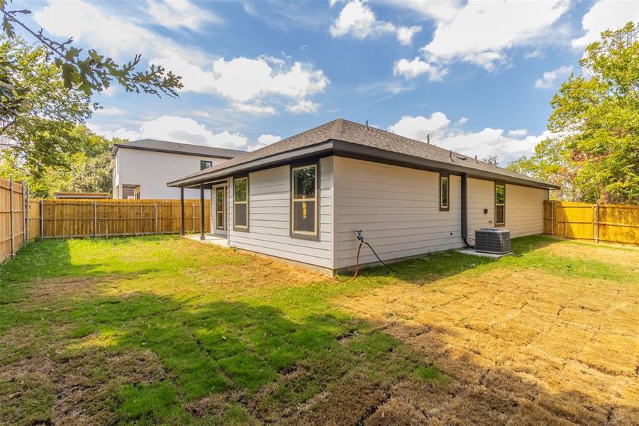 Rear view of property featuring a lawn and central air condition unit