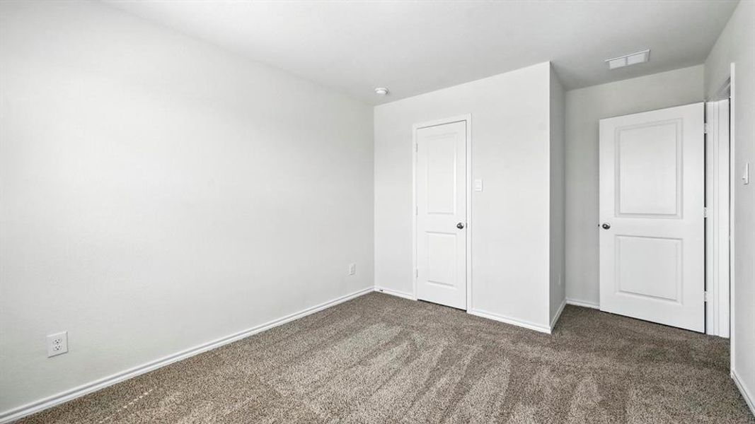 Unfurnished bedroom with dark carpet and baseboards