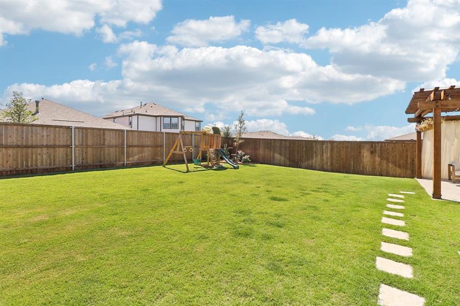 Fenced backyard with a playground and a pergola Fenced backyard with a playground and a pergola