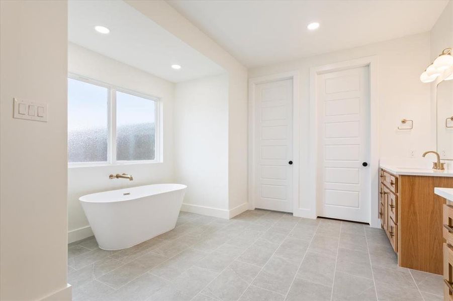 Bathroom featuring vanity, a soaking tub, and recessed lighting