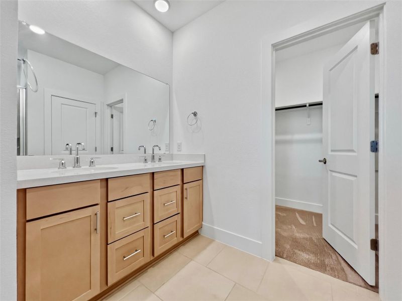 Bathroom with double vanity, a spacious closet, and light tile patterned flooring