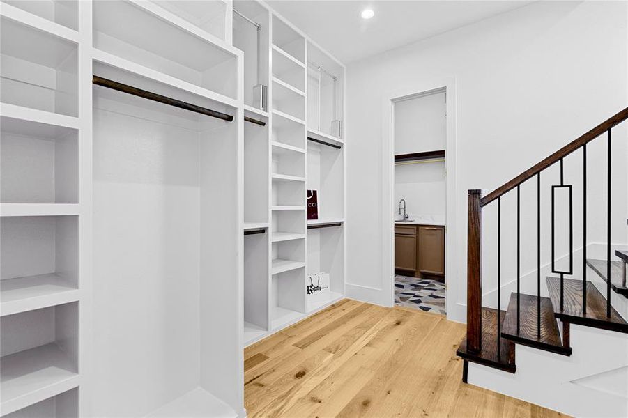 His closet with custom shelving and cabinets. Stairs lead up to her closet and access to the laundry room. His closet with custom shelving and cabinets. Stairs lead up to her closet and access to the laundry room.