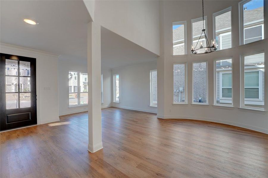 Foyer entrance with baseboards, ornamental molding, a high ceiling, vinyl flooring, and a notable chandelier