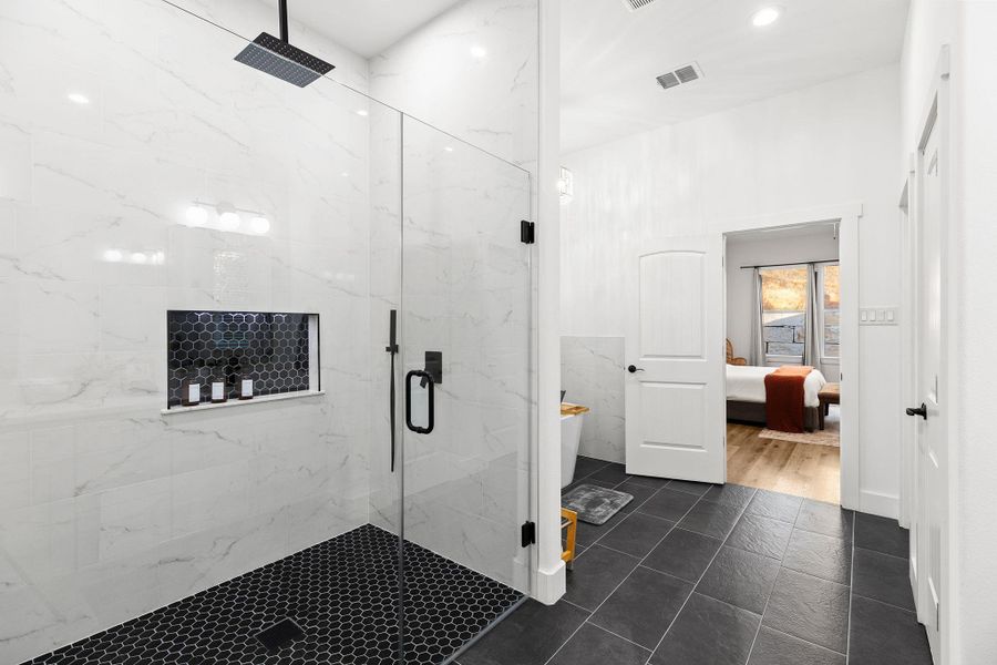 Ensuite bathroom featuring a marble finish shower, a freestanding tub, recessed lighting, and dark tile patterned flooring