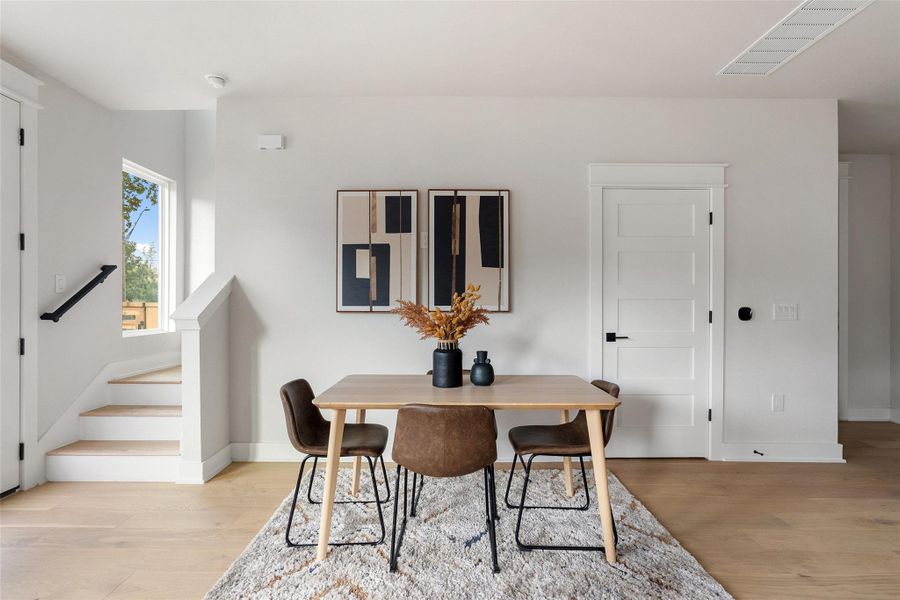Dining space featuring stairs and light wood-style flooring Dining space featuring stairs and light wood-style flooring
