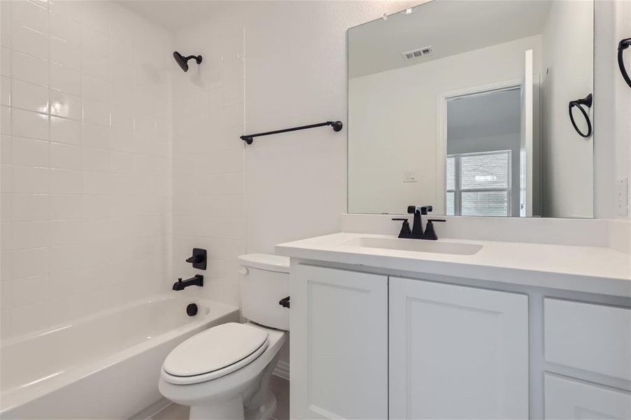 Full bathroom with tiled shower / bath, vanity, and toilet