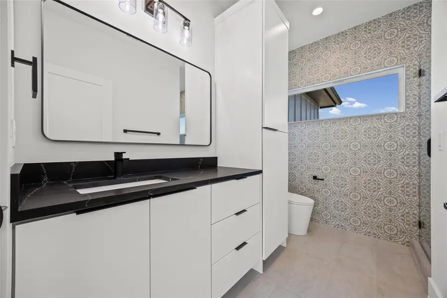 Bathroom featuring vanity, wallpapered walls, a shower with door, and light tile patterned flooring Bathroom featuring vanity, wallpapered walls, a shower with door, and light tile patterned flooring