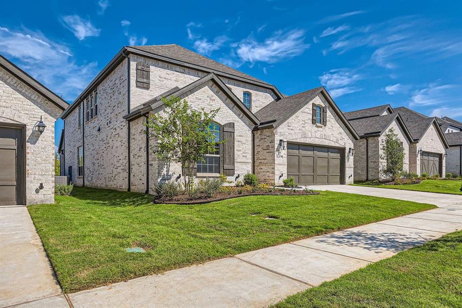 French country home featuring a garage and a front yard