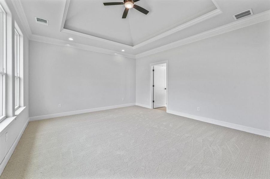 Spare room with a raised ceiling, ceiling fan, crown molding, recessed lighting, and light colored carpet