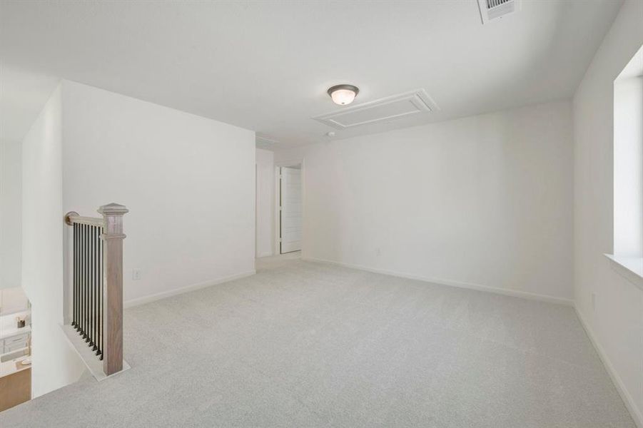 Carpeted room featuring a window, ceiling-mounted light fixture, and a stair railing with wood and metal elements