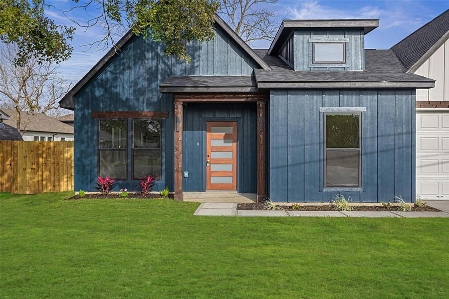 Inviting covered porch with modern wood and glass front door, statement beams, and stylish exterior finishes.